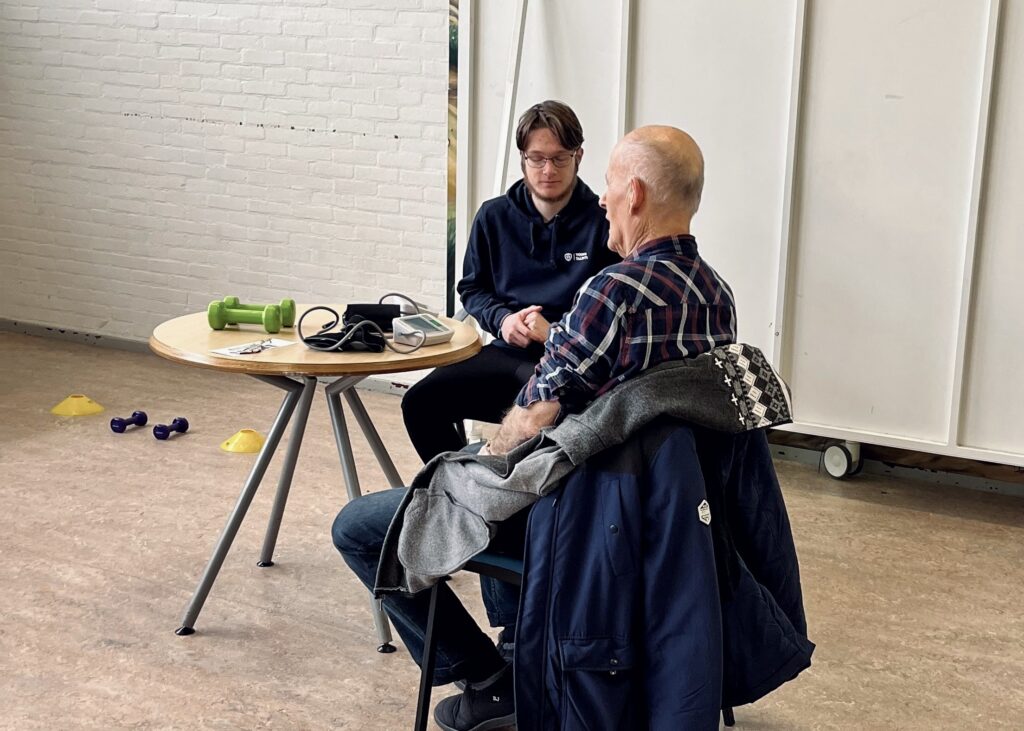 Student die een oudere man helpt om zijn vitaliteit in kaart te brengen